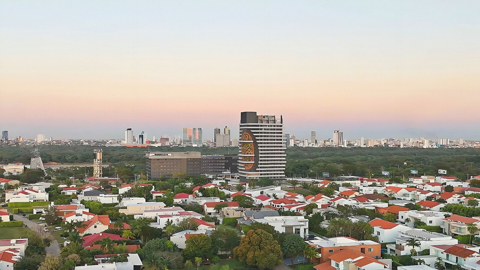 Horizonte de la zona norte de Santa Cruz al atardecer: casas de techo rojo y, al fondo, las torres de Equipetrol