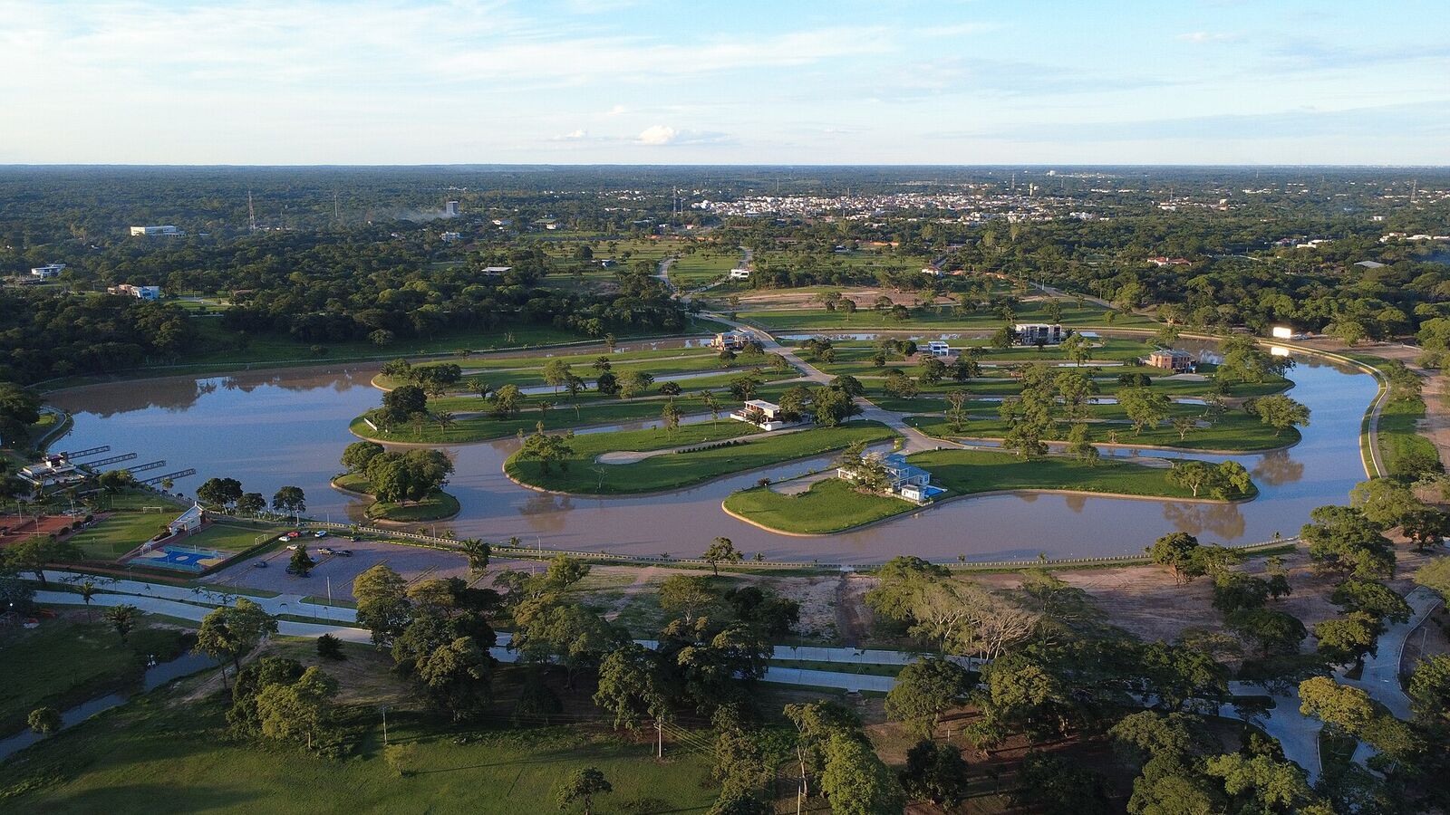 Laguna y lotes con árboles de un condominio del Urubó, vistos desde el aire, con la llanura al fondo
