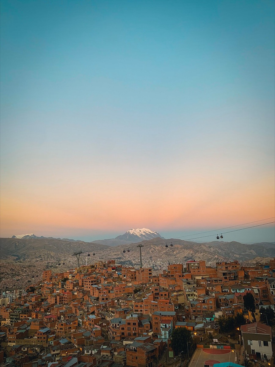 La ciudad de La Paz al atardecer con el nevado Illimani al fondo y cabinas del teleférico